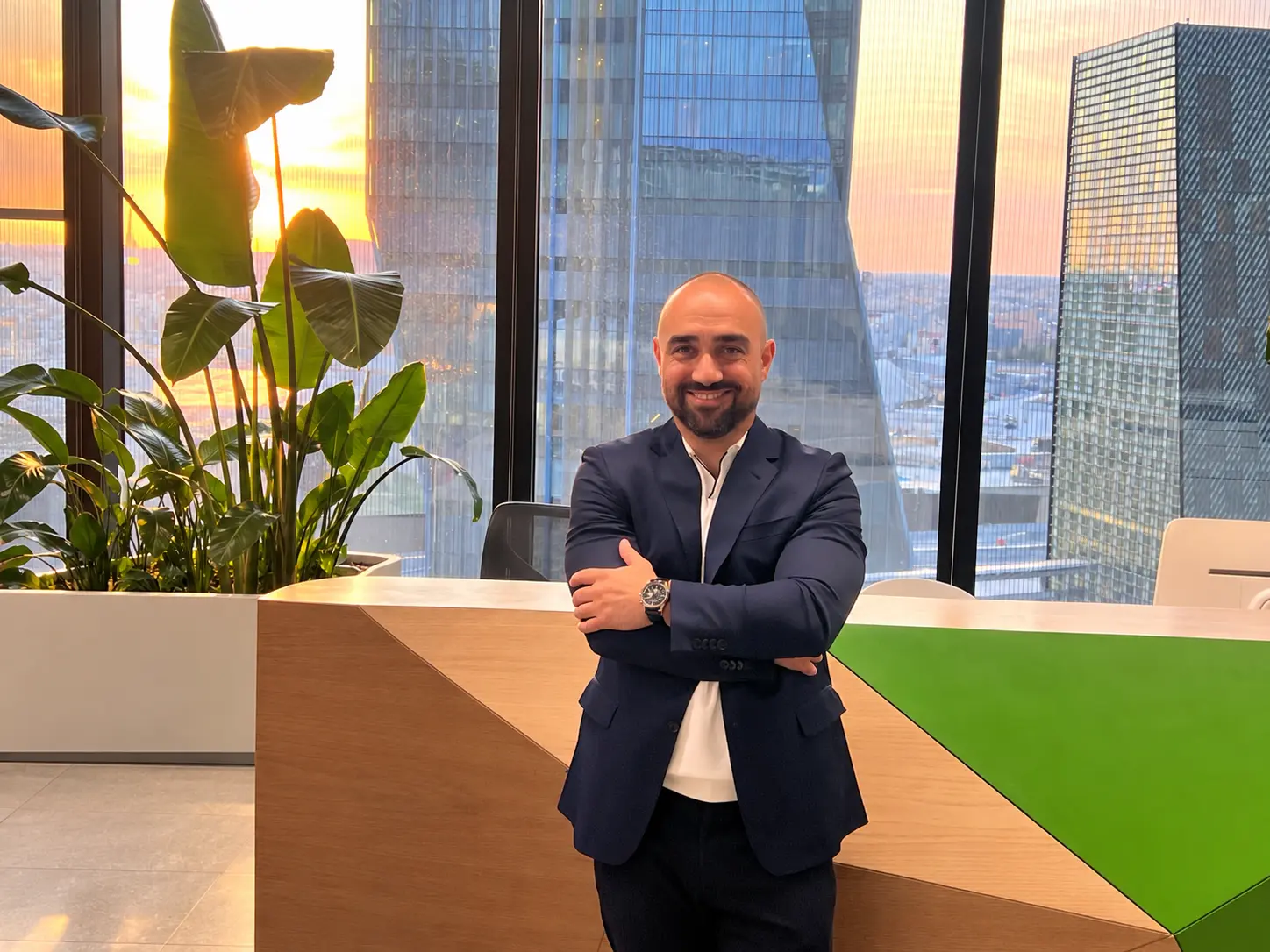 Mohamad Mosleh standing in a bright office with a city skyline behind him